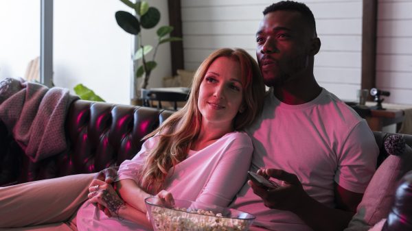 A couple is eating popcorn and watching a movie