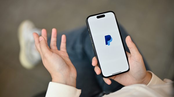 An Asian woman using PayPal application on her iPhone14 while relaxing in a coffee shop