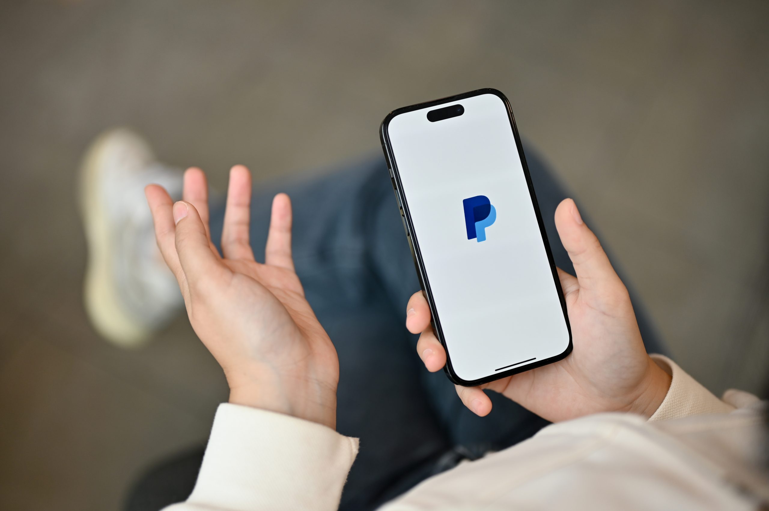 An Asian woman using PayPal application on her iPhone14 while relaxing in a coffee shop