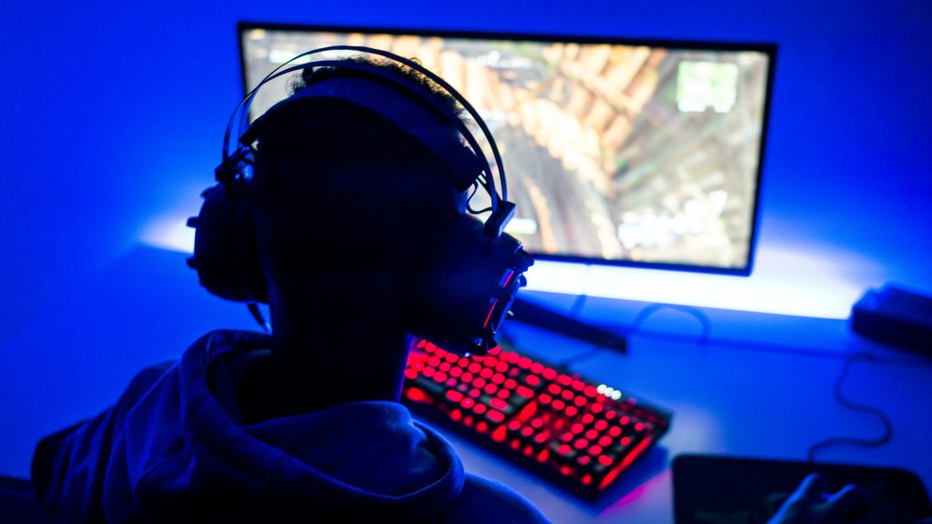 A young man with headphones playing a computer video game.