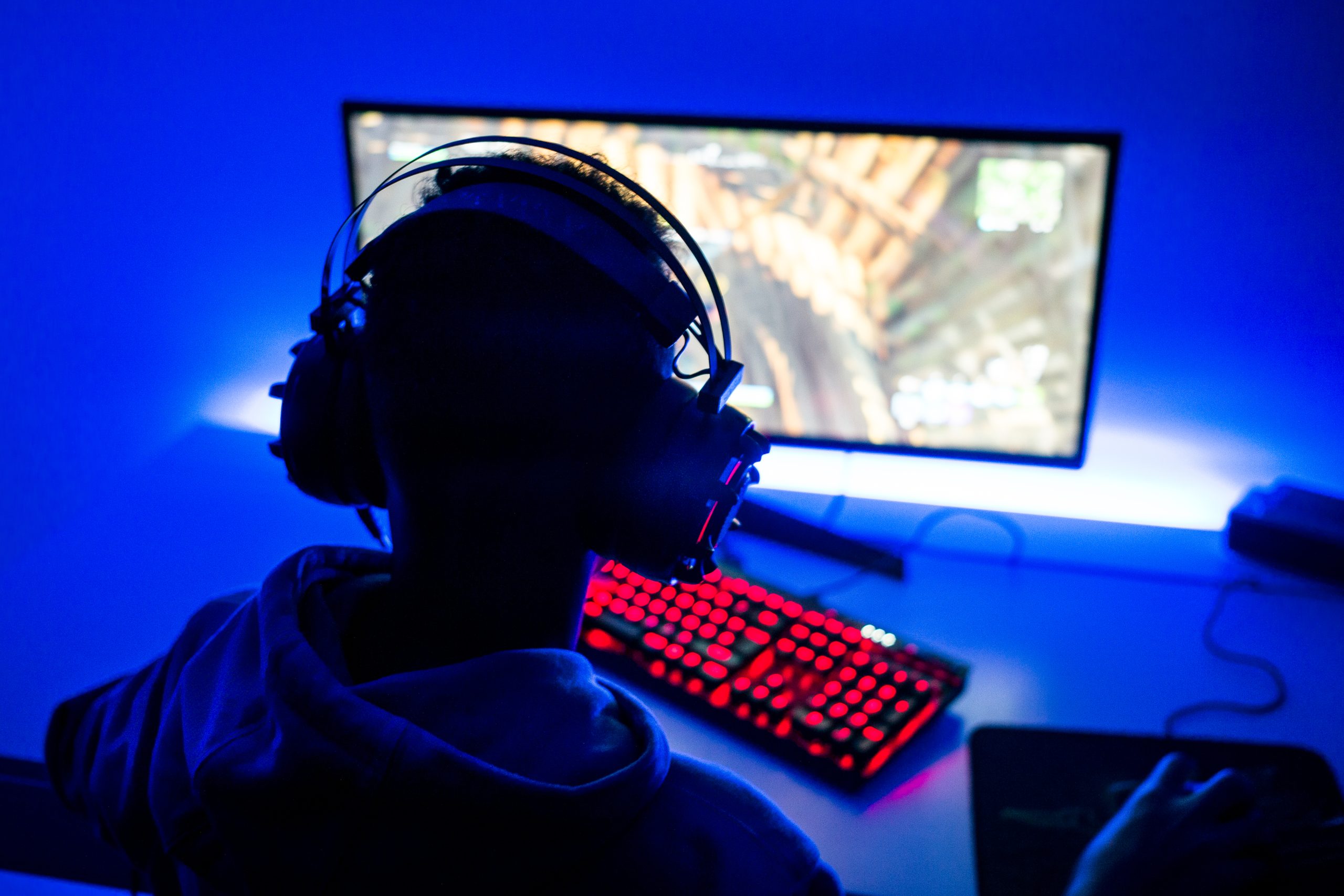 A young man with headphones playing a computer video game.