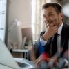 Smiling mid adult businessman using computer while working at office desk