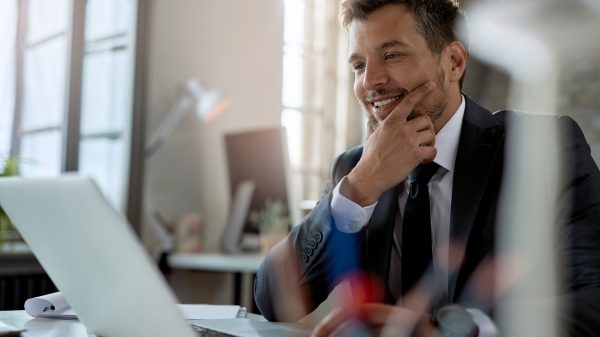 Smiling mid adult businessman using computer while working at office desk