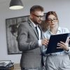 Woman with glasses. Businessman with documents. Colleagues work together.