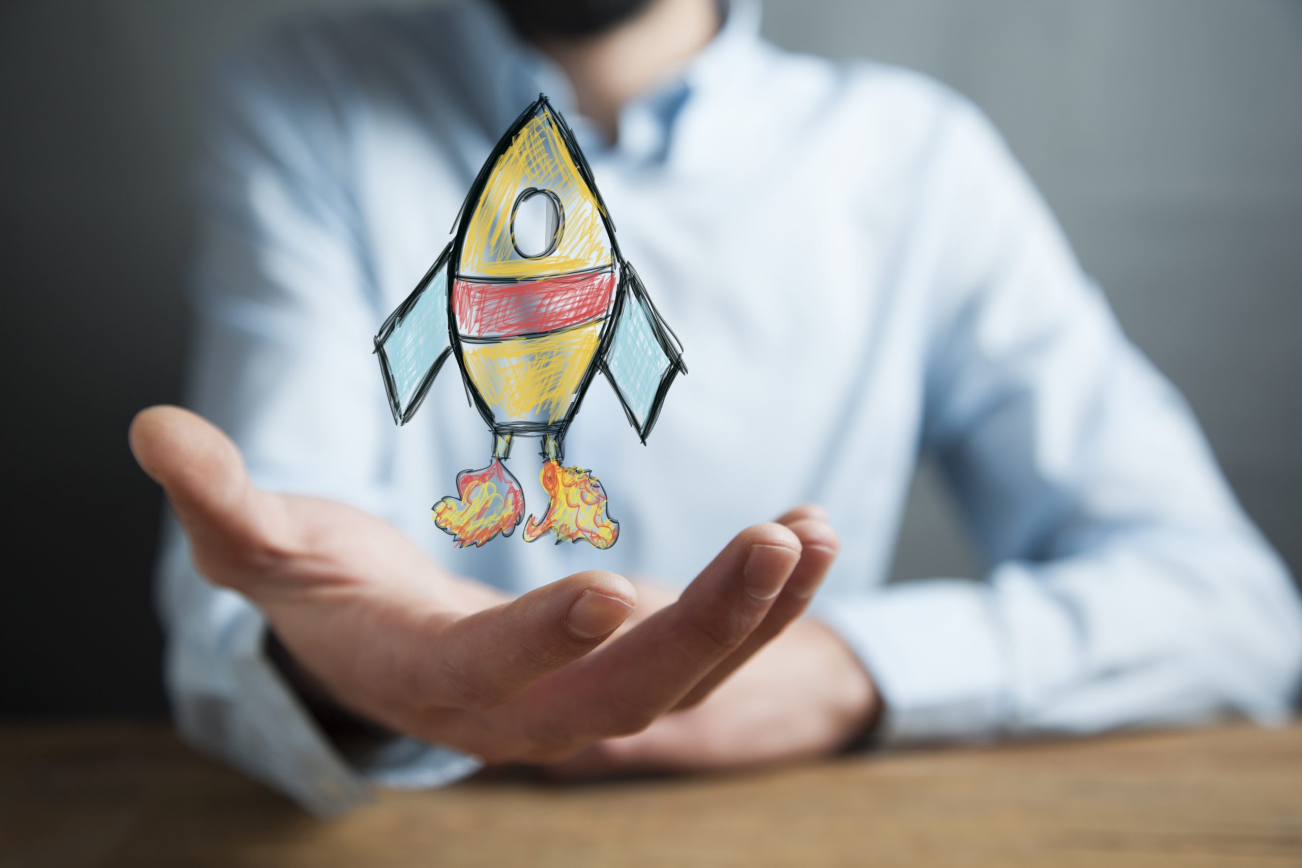 Man hand holding rocket on table background